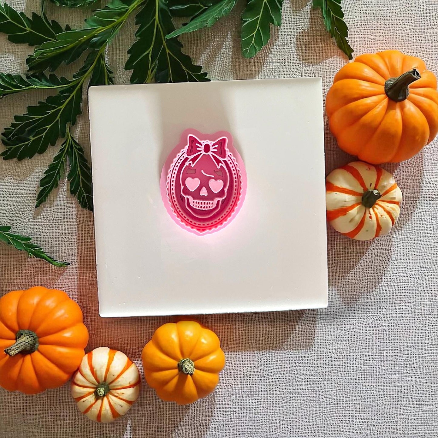 Pink girly skull cameo cutter with bow and heart eyes surrounded by pumpkins