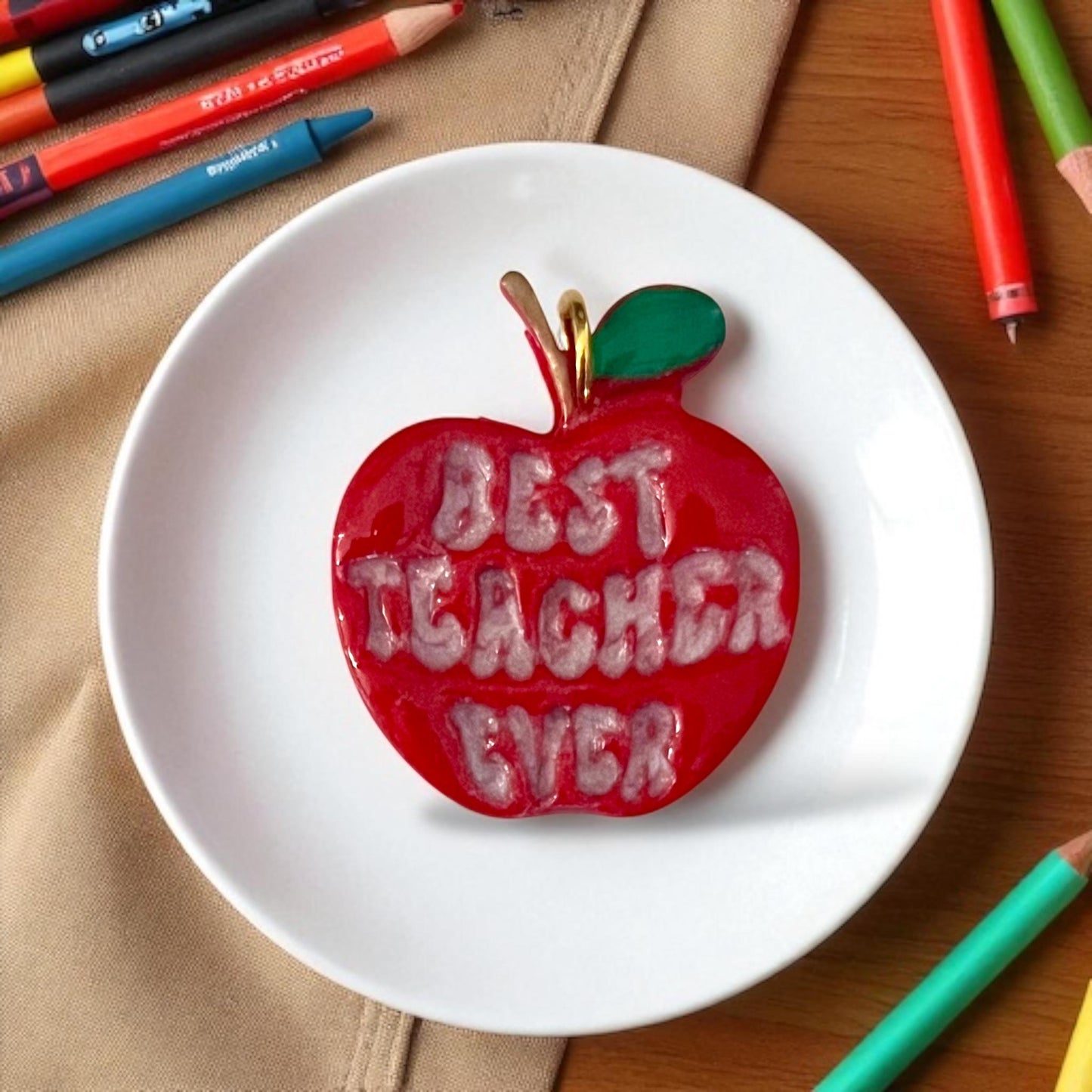 painted best teacher ever apple clay piece in red with green leaf on white plate