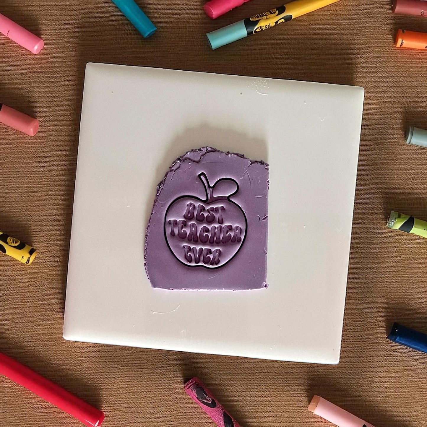 best teacher ever apple clay impression on purple clay sheet surrounded by crayons