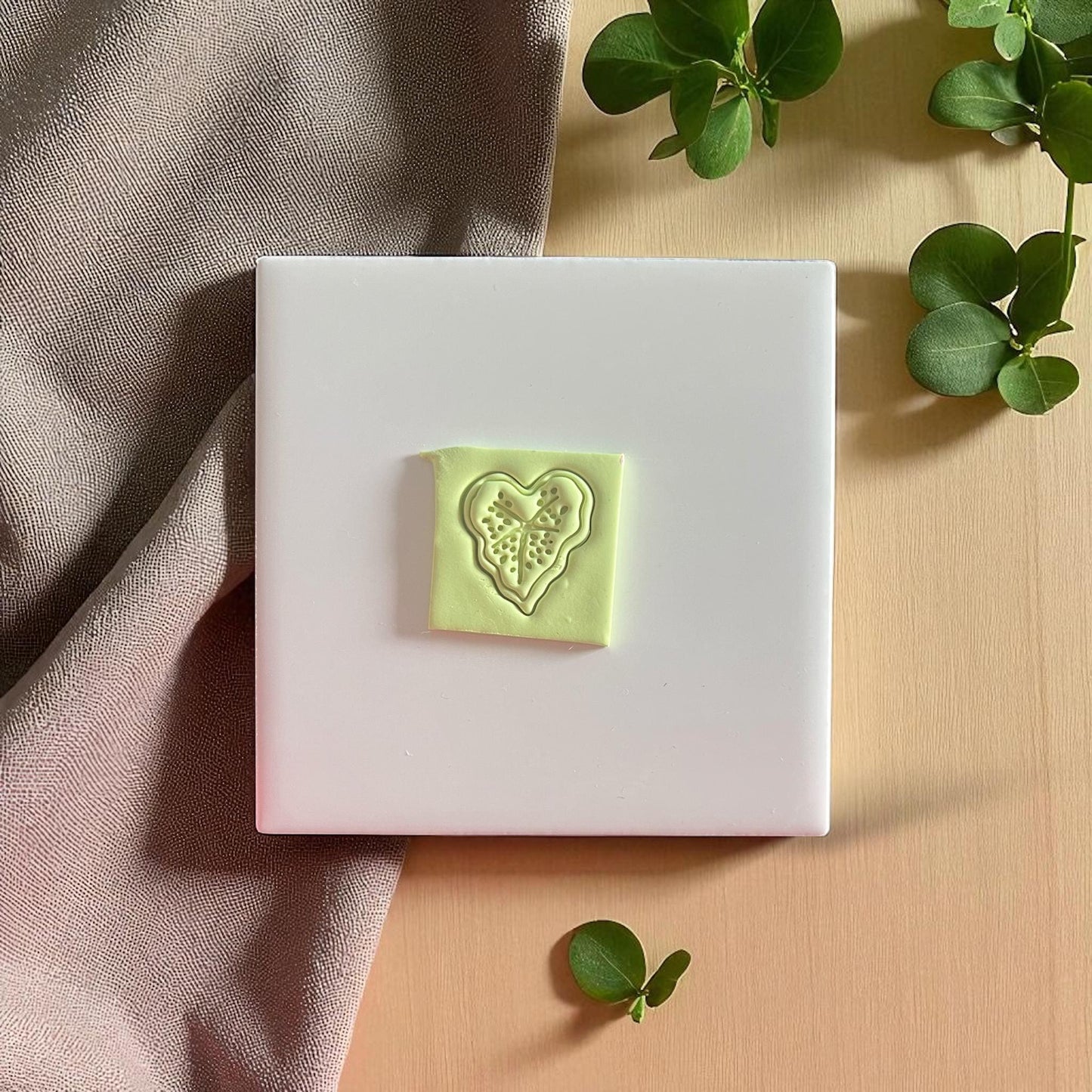 Caladium heart leaf clay impression on white tile