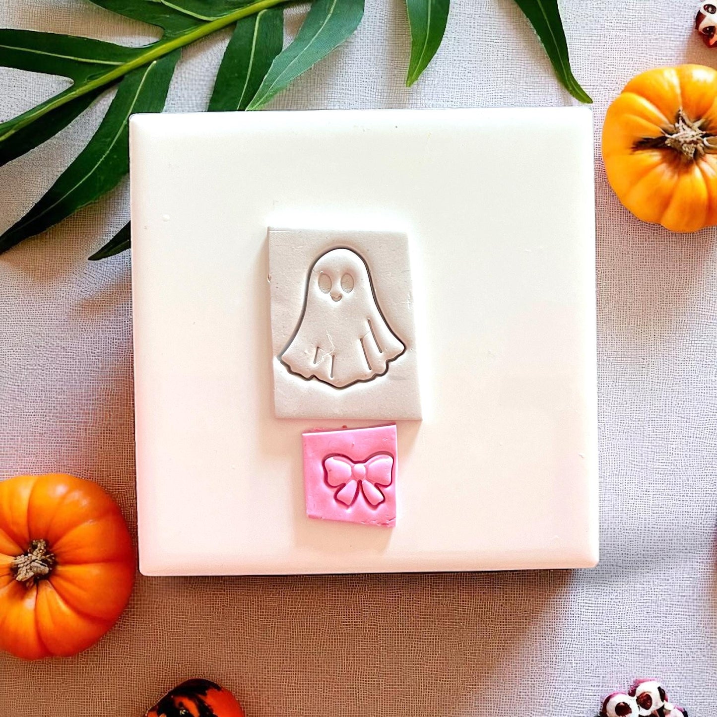 Ghost and bow clay imprint on white tile with pumpkins