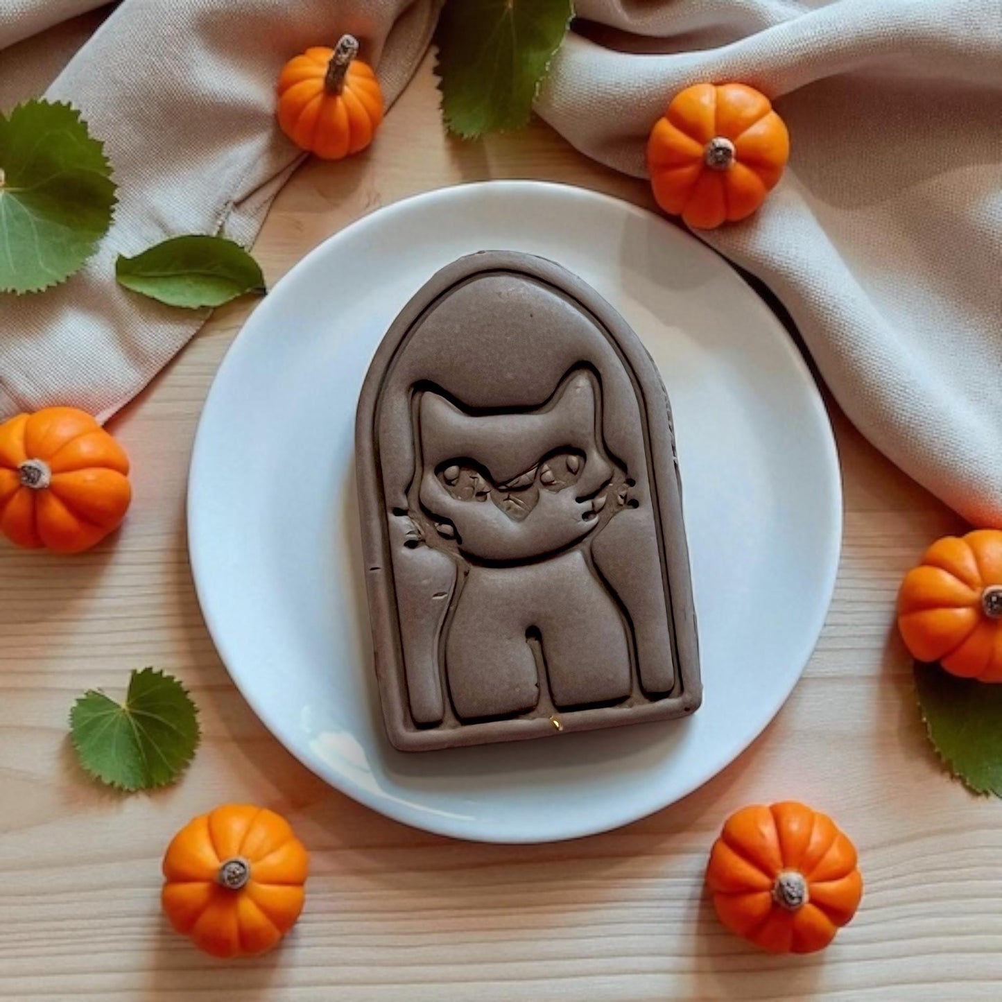 Full spooky cat impression in chocolate clay surrounded by mini pumpkins