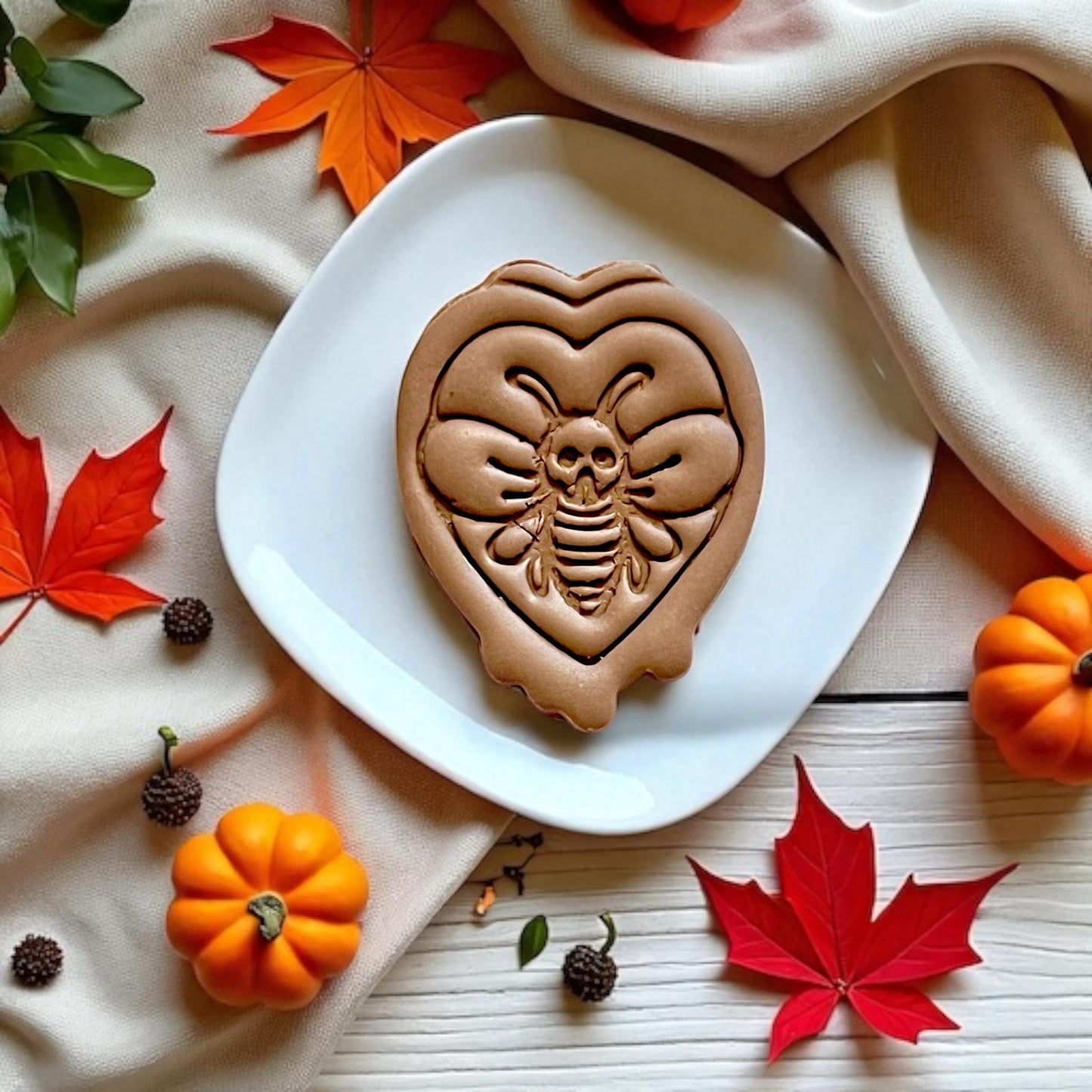 Finished gothic skull moth clay piece on white plate with autumn leaves and decor
