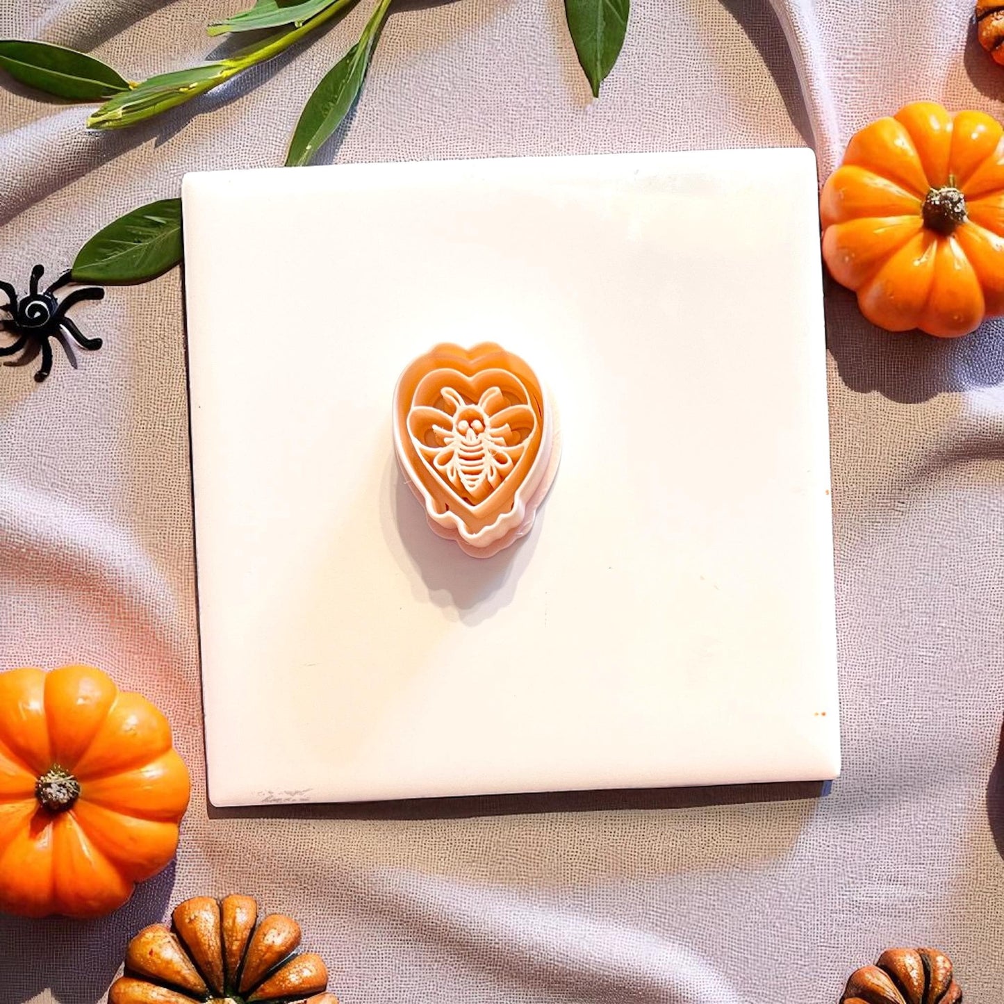 Orange cutter with skeletal moth detail displayed on tile with pumpkins