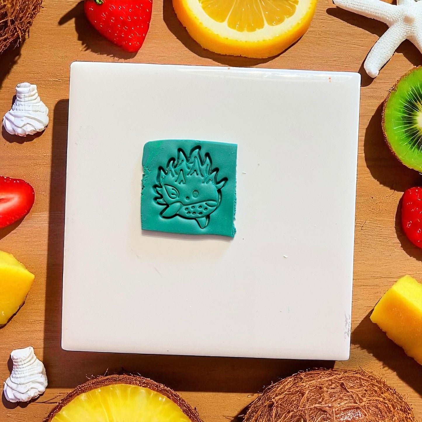 Close-up of pomegranate whale clay imprint on teal slab