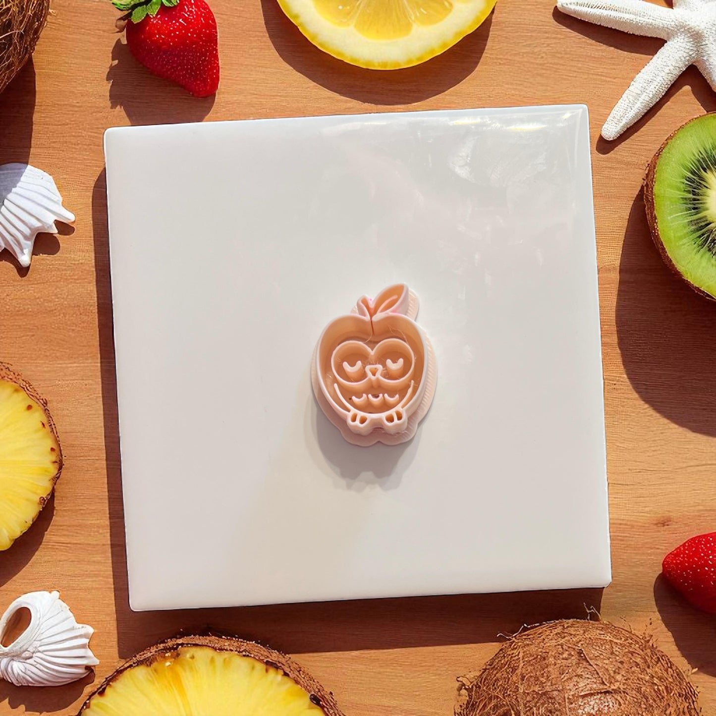 Apple owl polymer clay cutter alone with tropical fruit background