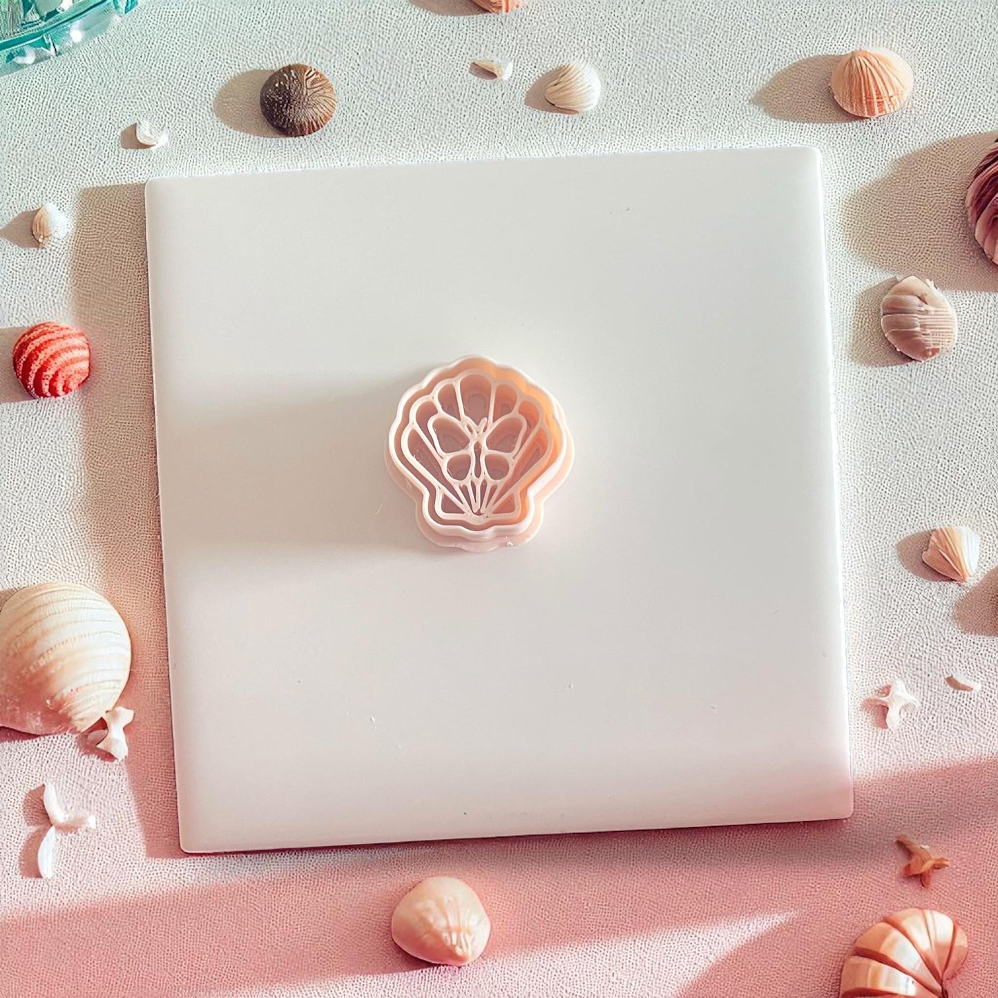 Peach-toned shell butterfly polymer clay cutter on white tile
