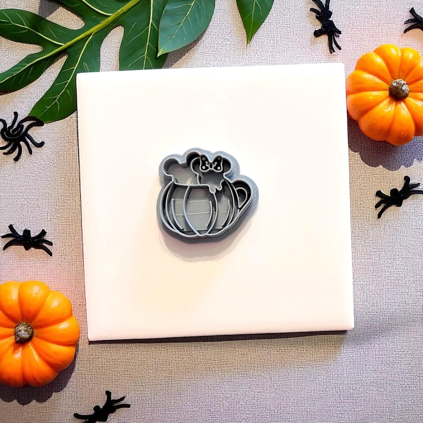 Grey pumpkin mug clay cutter surrounded by pumpkins and Halloween props