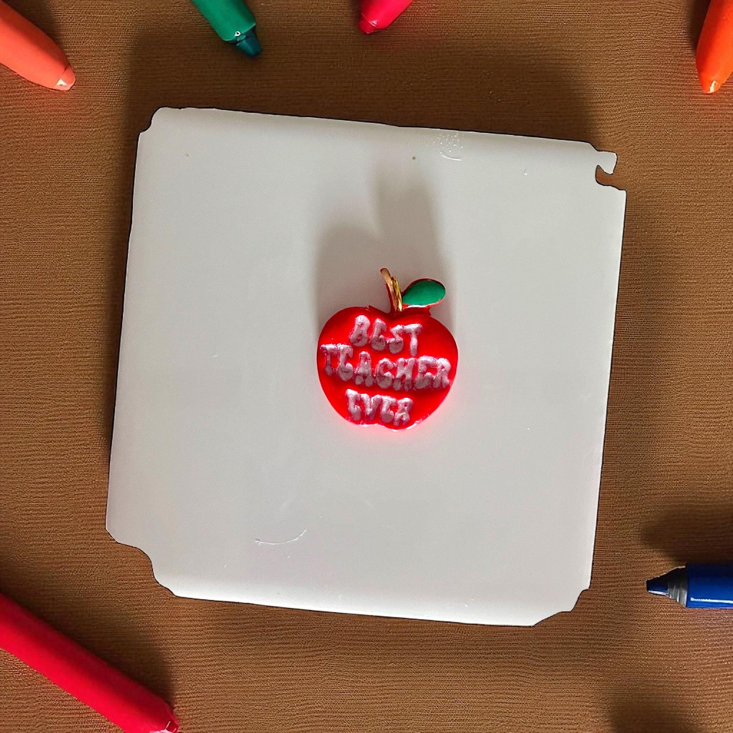 painted best teacher ever apple clay piece in red with green leaf on white tile