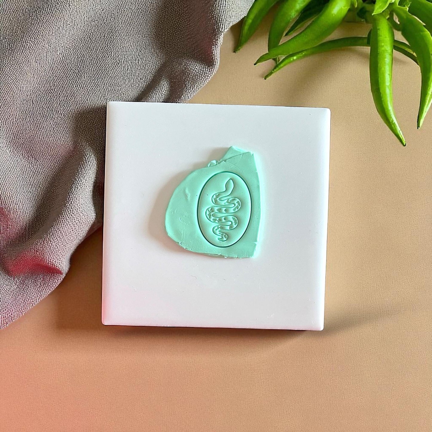 Teal snake clay impression on white tile