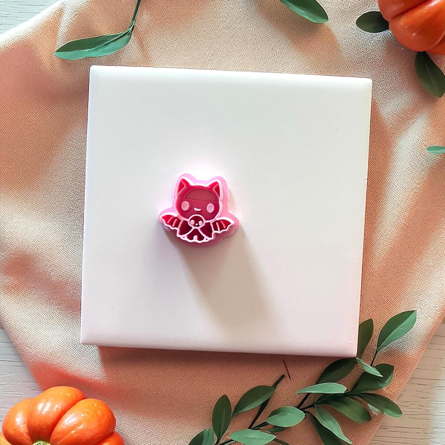 Pink baby bat cutter shown on white tile with greenery and pumpkins.