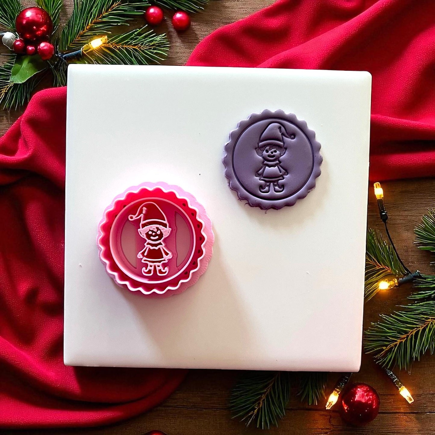 Purple elf clay imprint on plate with Christmas lights and ornaments.