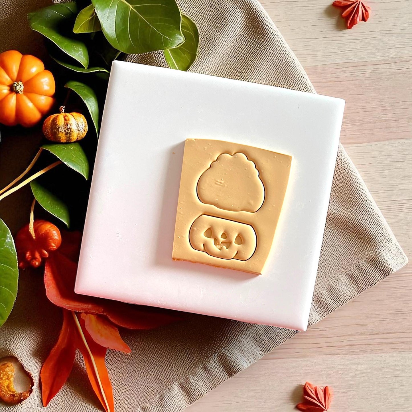 Pumpkin jack o lantern clay impressions with cutter outlines on beige fabric