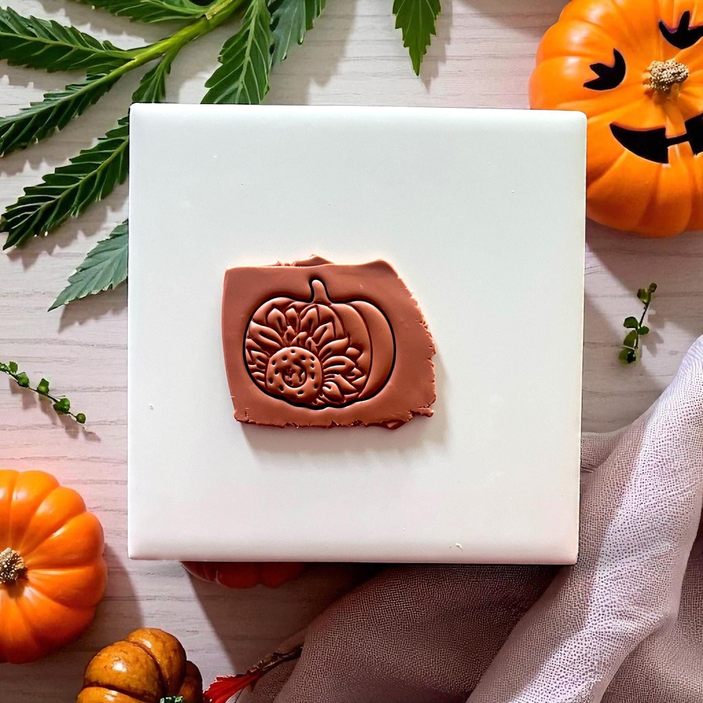 Clay impression of sunflower pumpkin design on brown clay