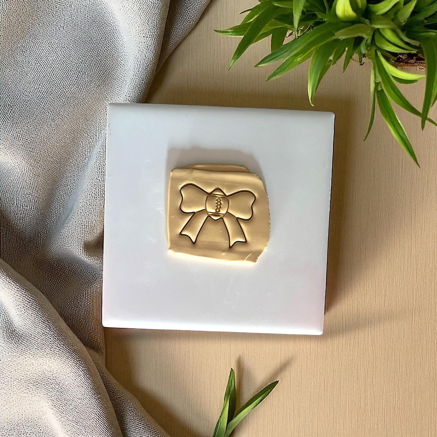 Football bow impression in clay on white tile