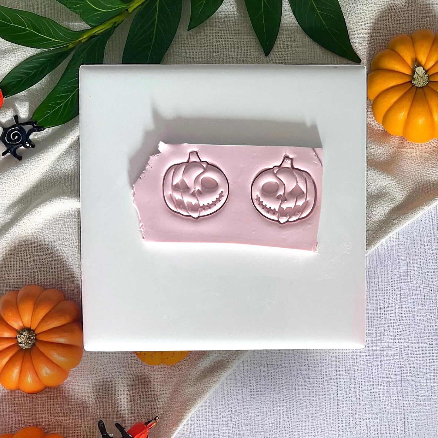 Pink imprints of pumpkin skull clay cutters on white tile
