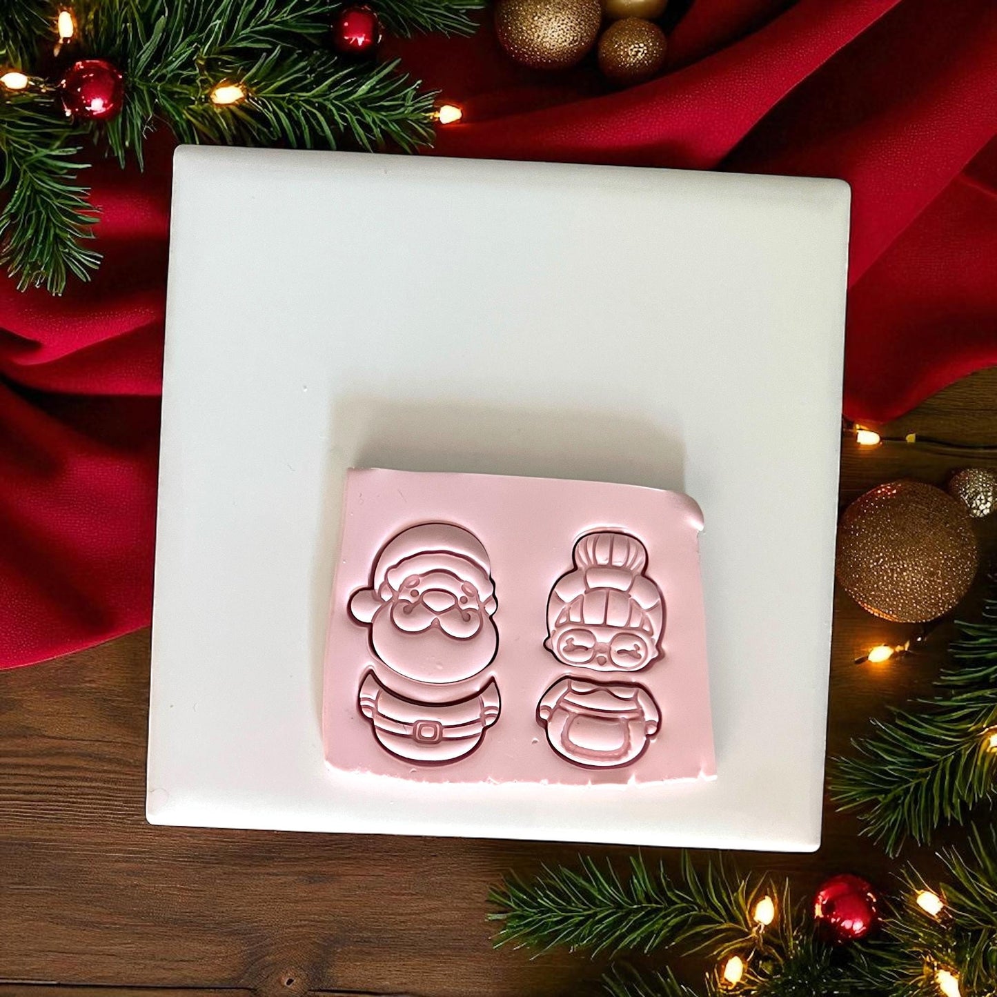 Santa and Mrs Claus clay cutter imprint in pink clay on white tile with Christmas decor