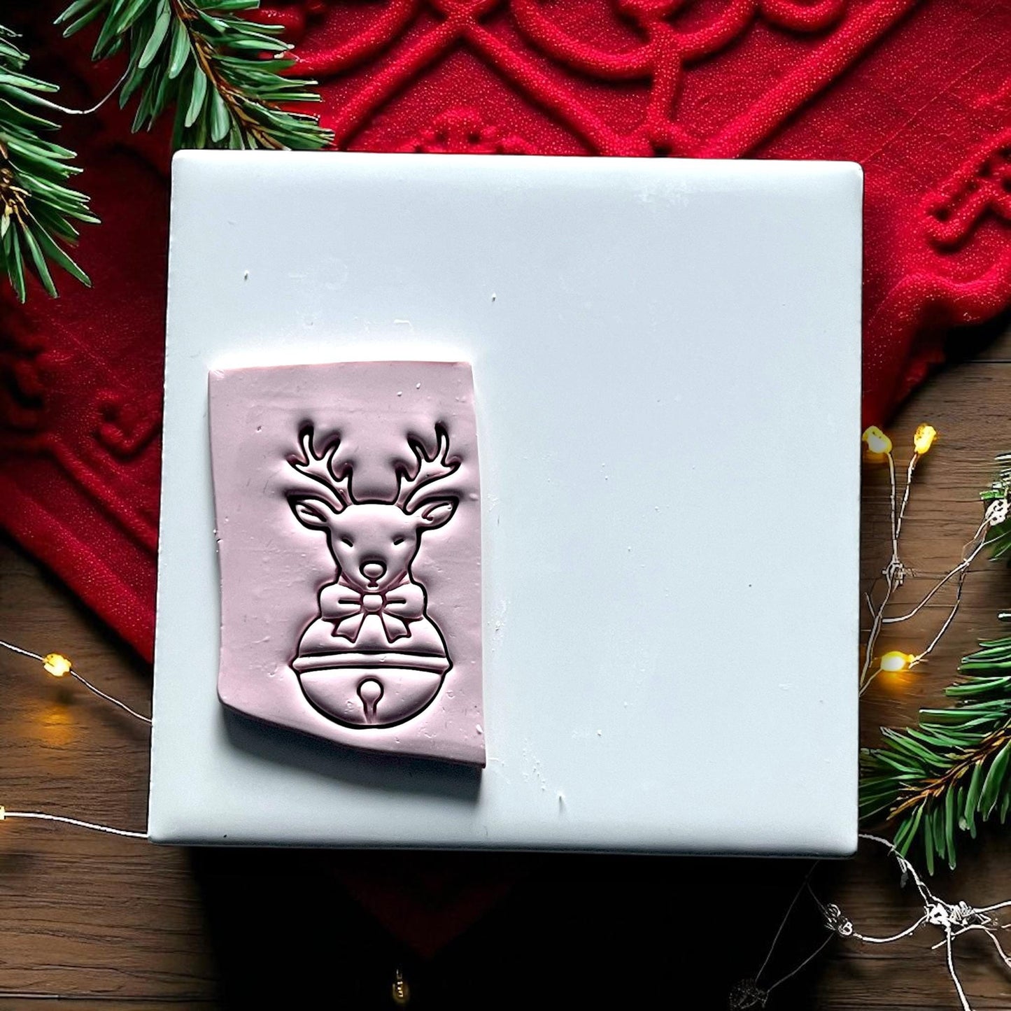 Red reindeer polymer clay cutter with bow and jingle bell on wood background