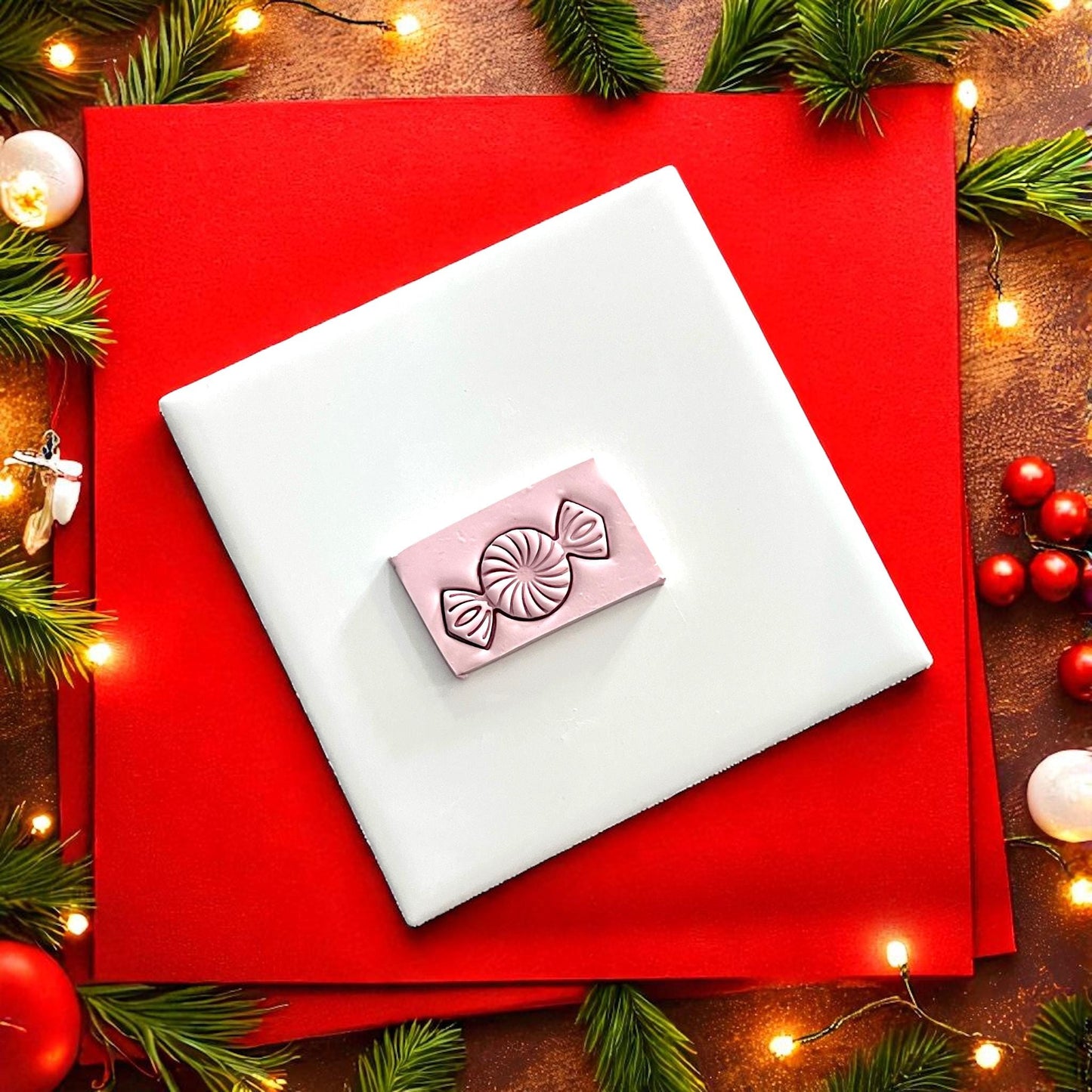 Peppermint candy polymer clay imprint on white tile with red holiday background