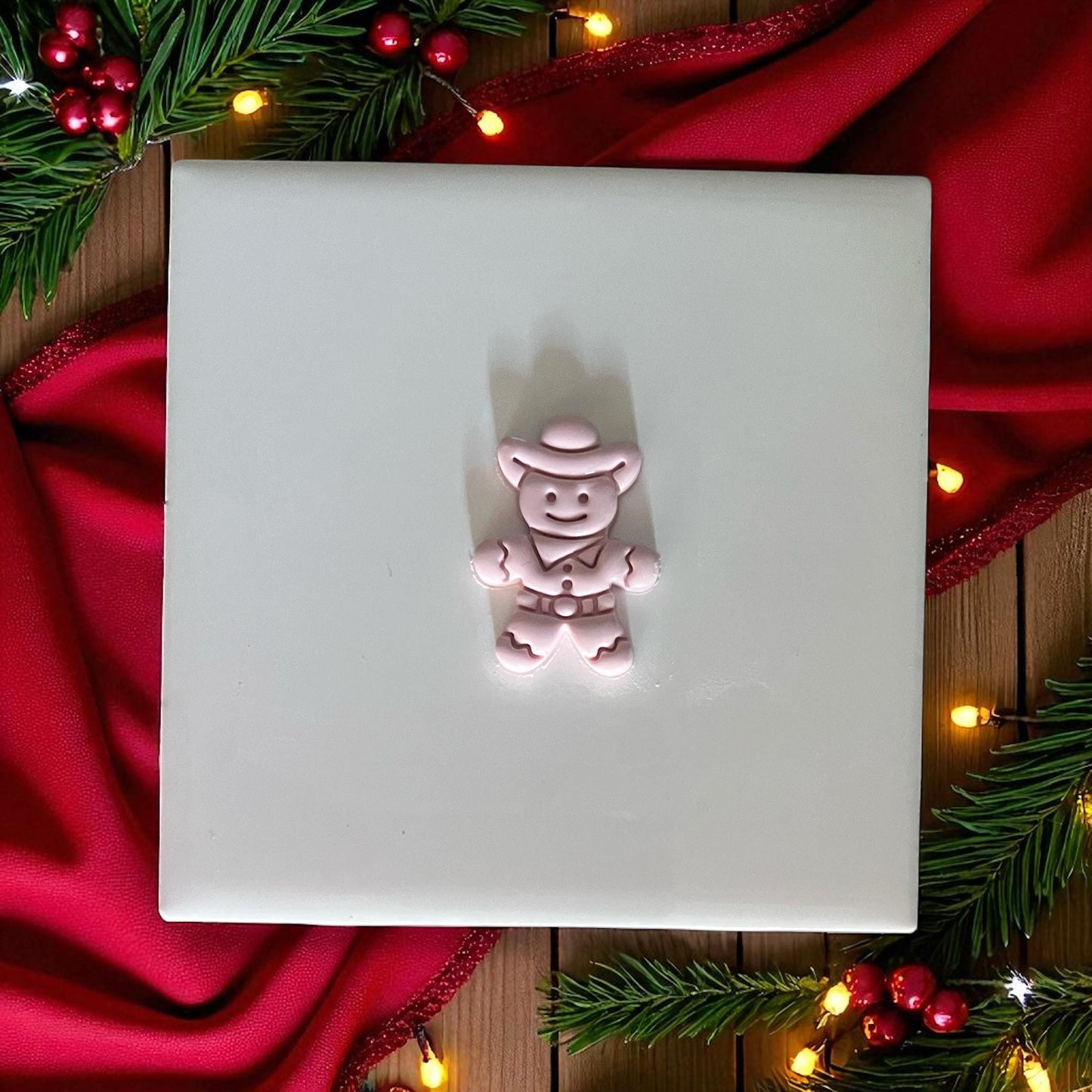 Small cowboy gingerbread clay imprint on white tile with red Christmas decor