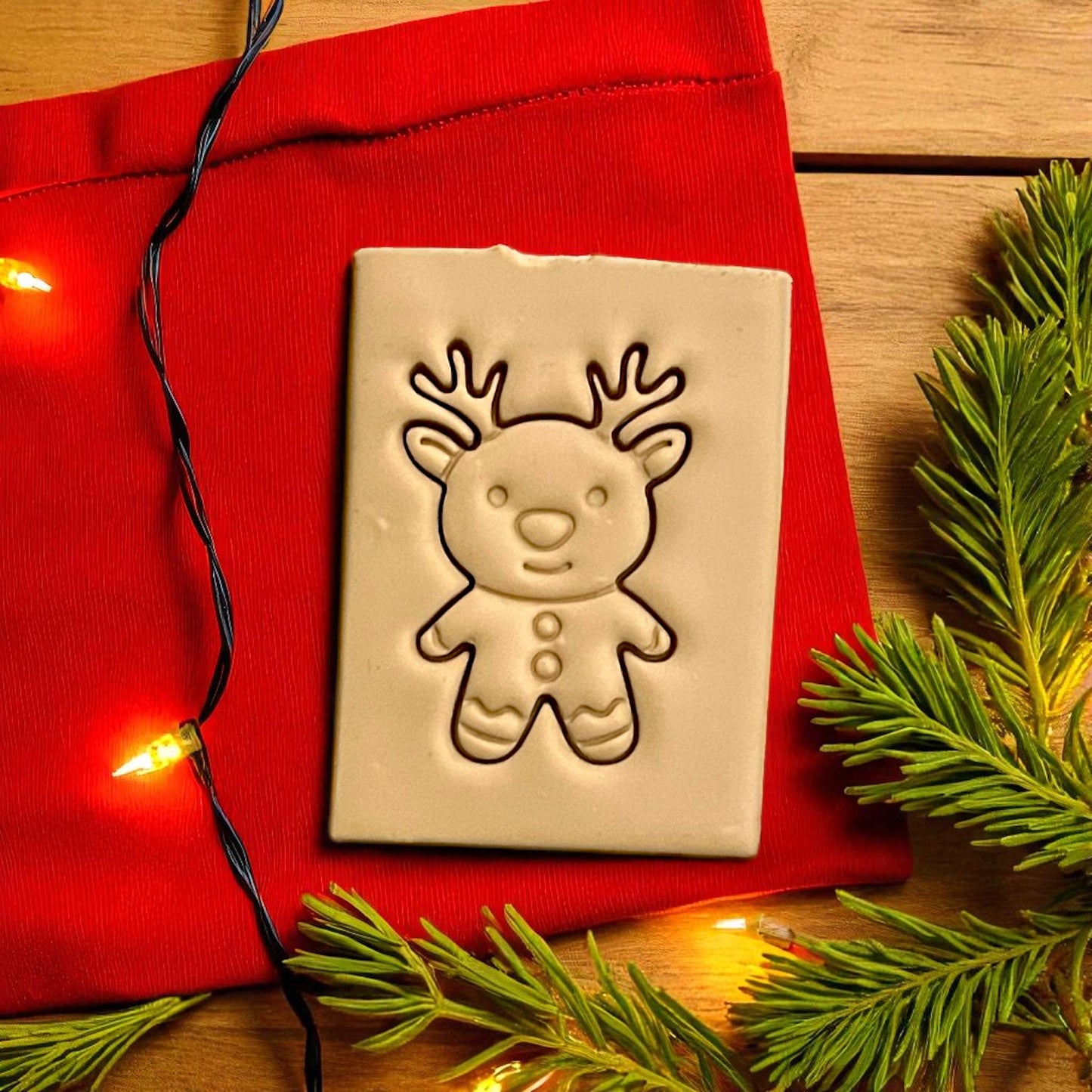 Gingerbread reindeer polymer clay imprint on red fabric with Christmas lights