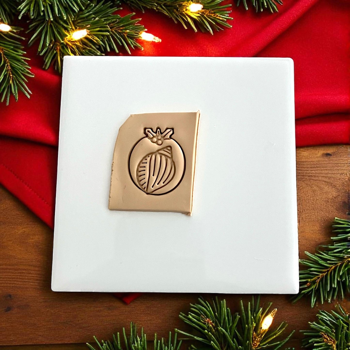 Christmas shell polymer clay cutter on white tile with red fabric and greenery