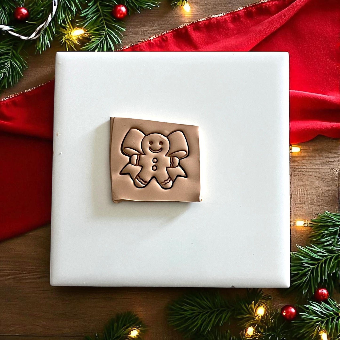 Square clay slab featuring gingerbread man bow impression for polymer clay design