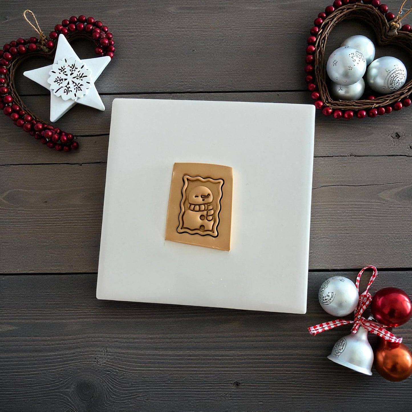 Tan snowman postage stamp clay imprint on wood background with Christmas ornaments