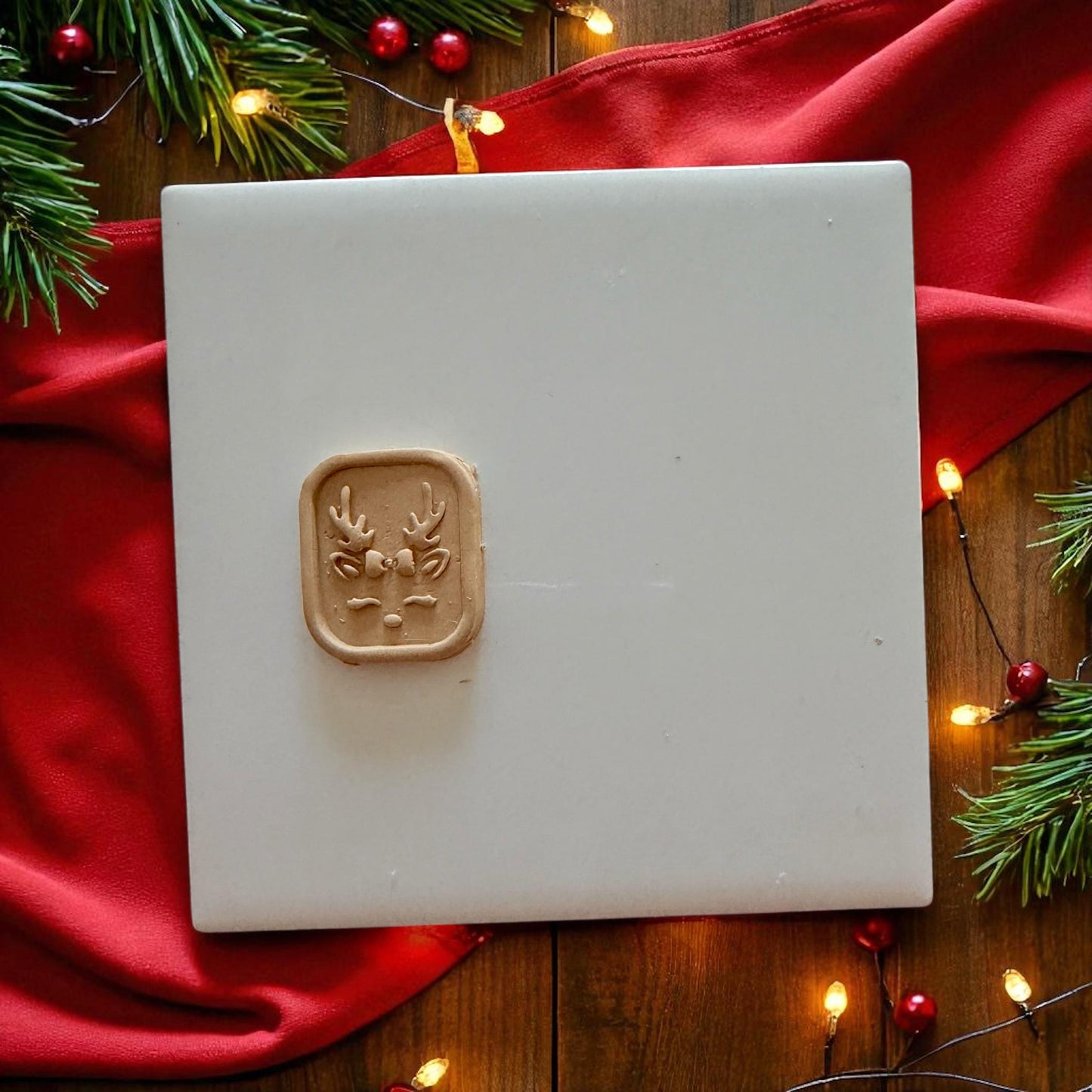 Small reindeer clay design centered on white tile with festive decor