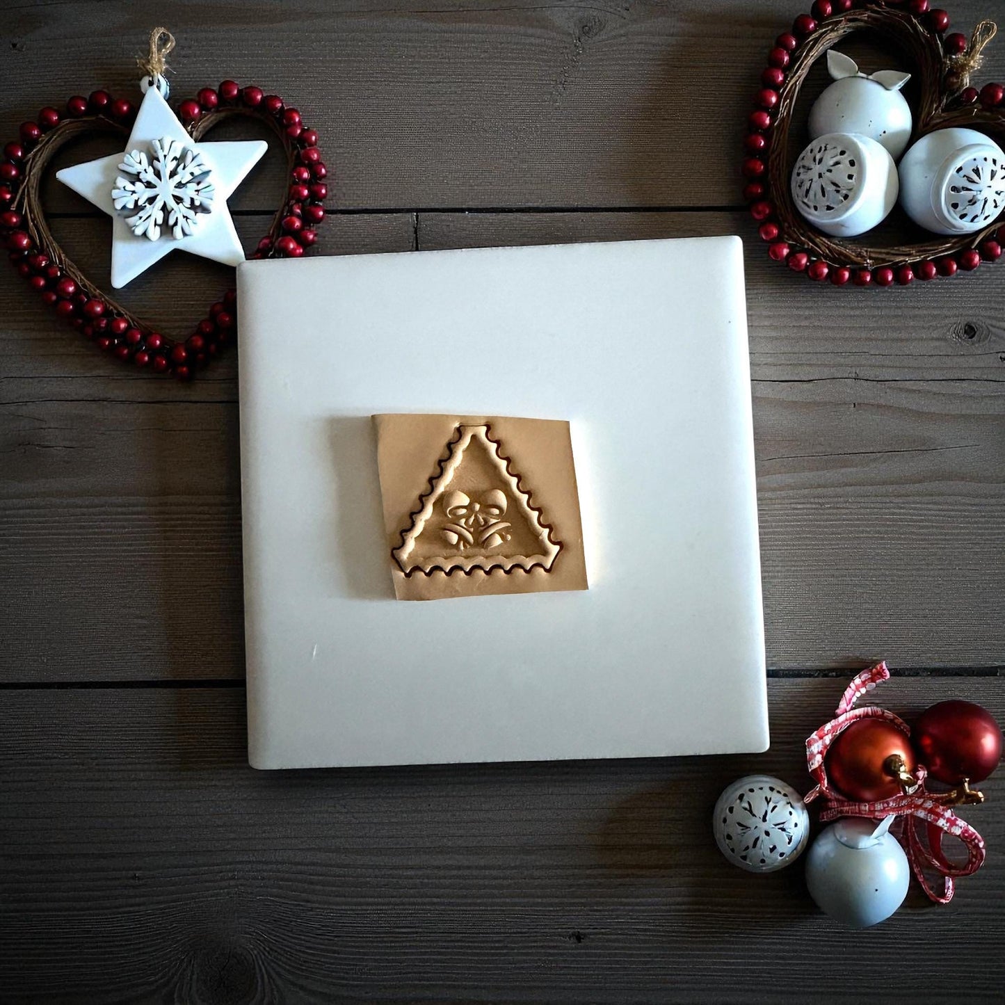 Triangle jingle bell clay imprint with bow detail on wood background with ornaments