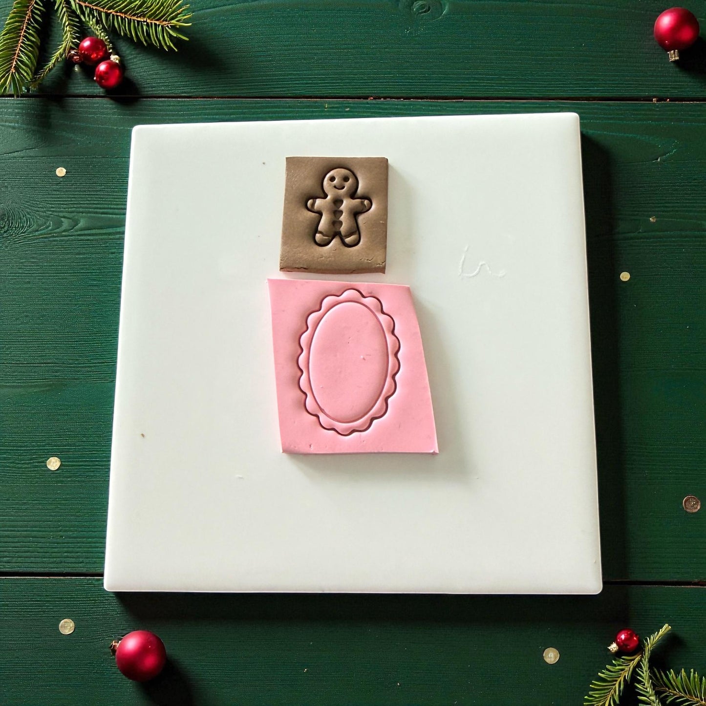 Brown gingerbread clay and pink scalloped oval impressions side by side on white tile
