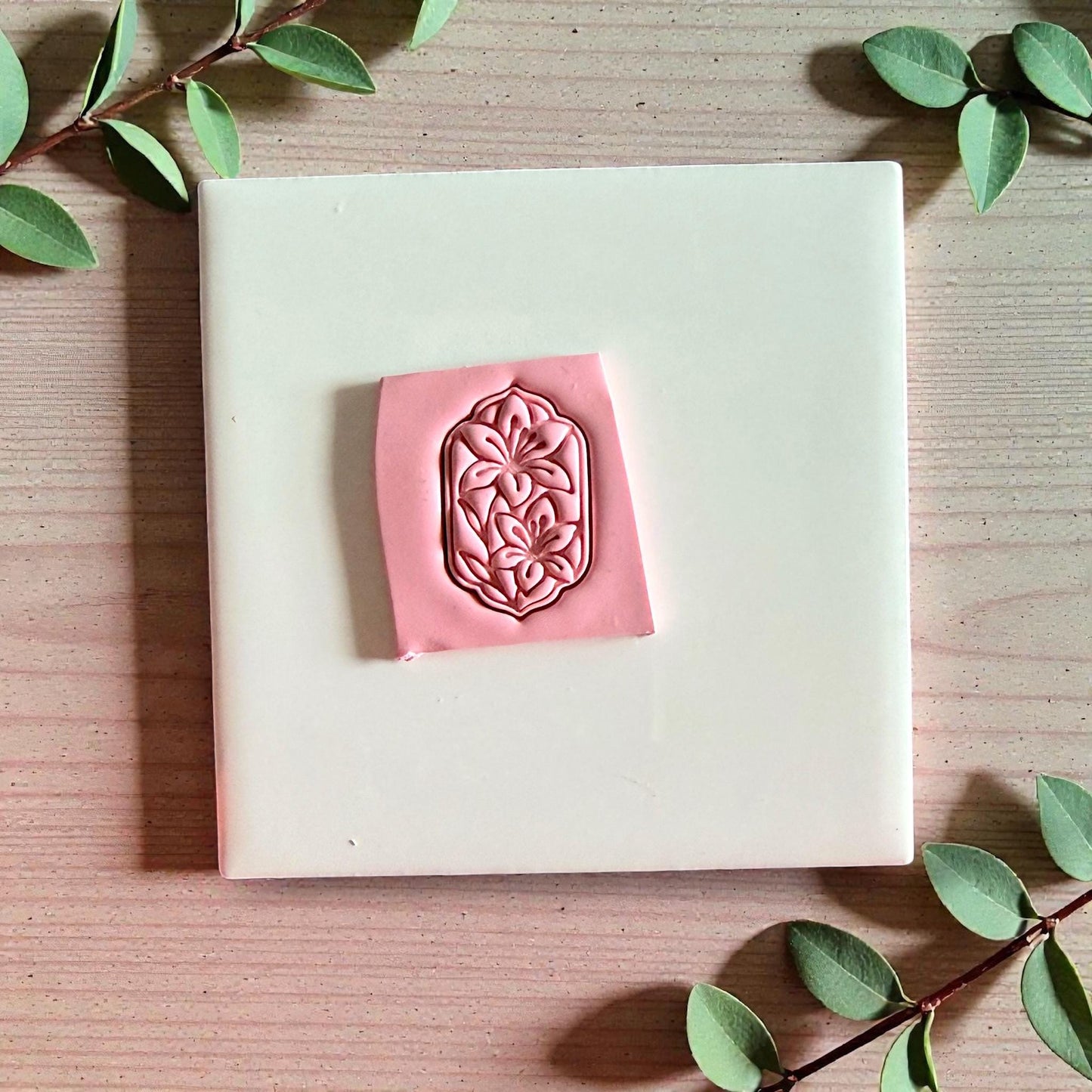 Pink lily floral impression on tile with green leaves