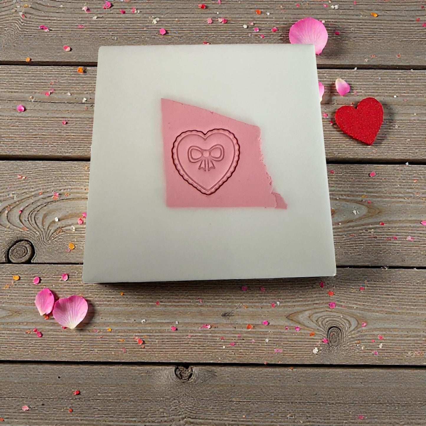 Heart bow clay impression on white tile with sprinkles around