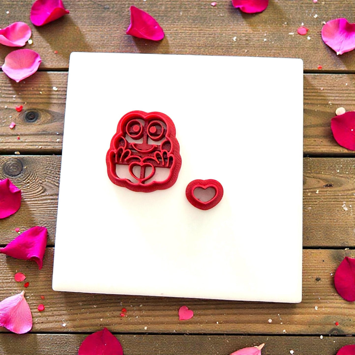 Red frog cutter next to clay frog surrounded by petals