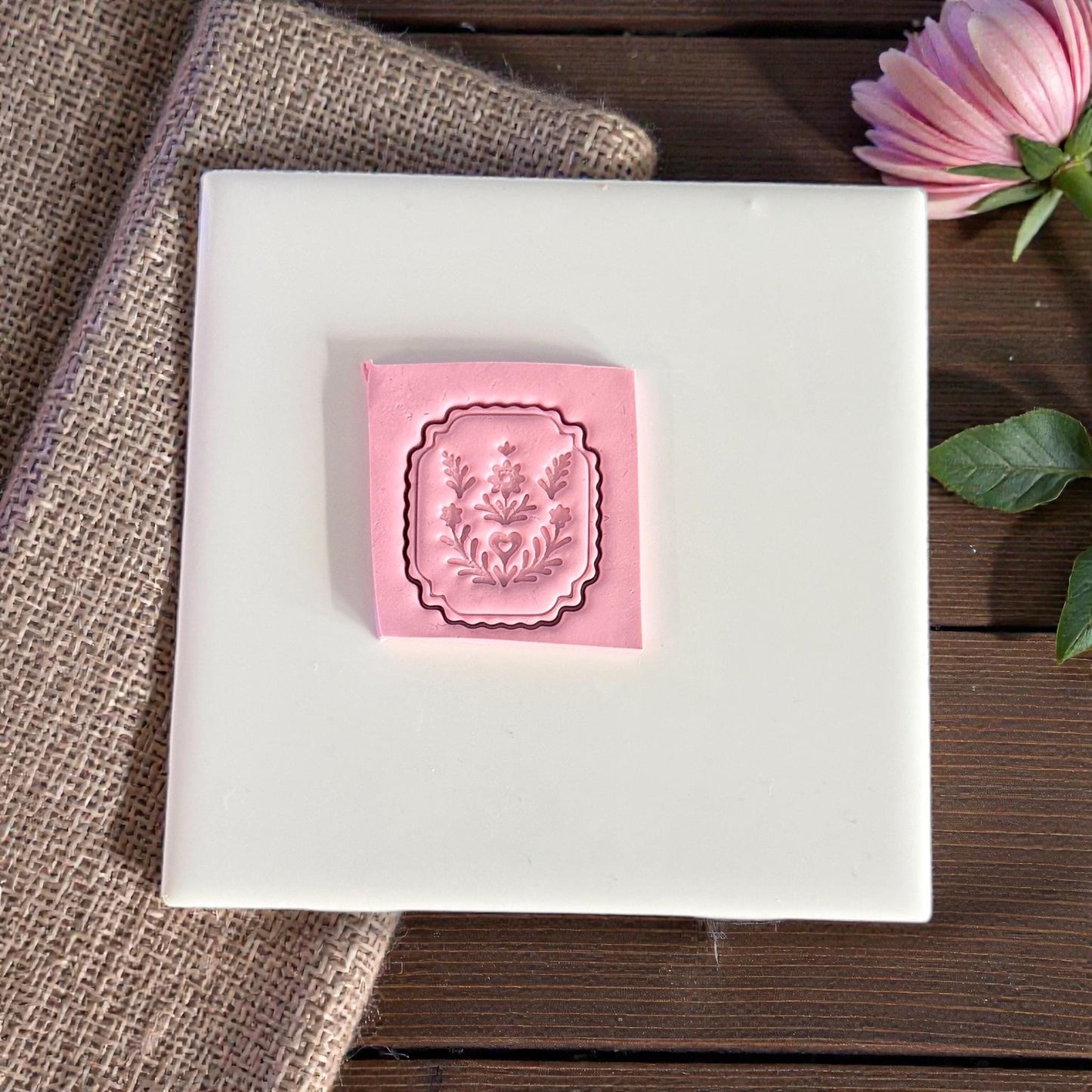 pink clay impression of folk floral plaque cutter on white tile