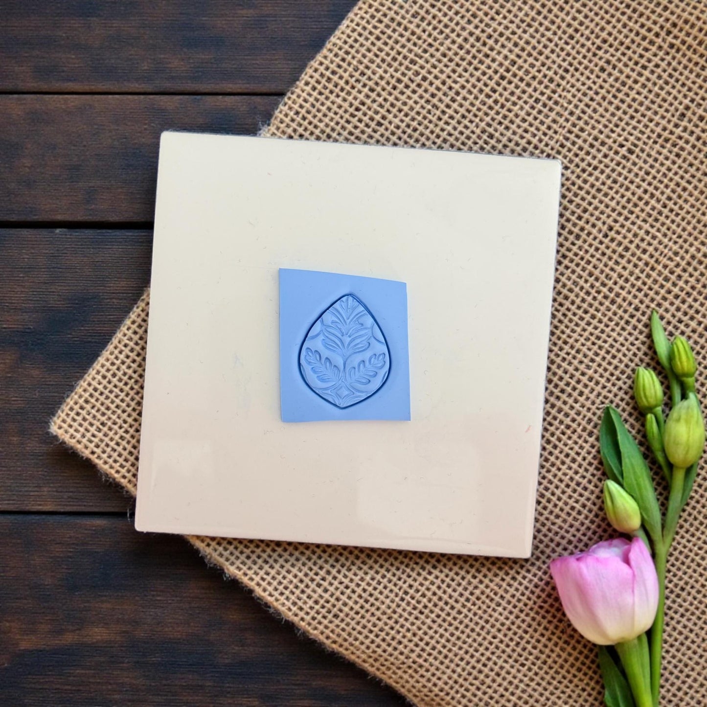 Leaf motif clay imprint cut from blue clay sheet on ceramic tile