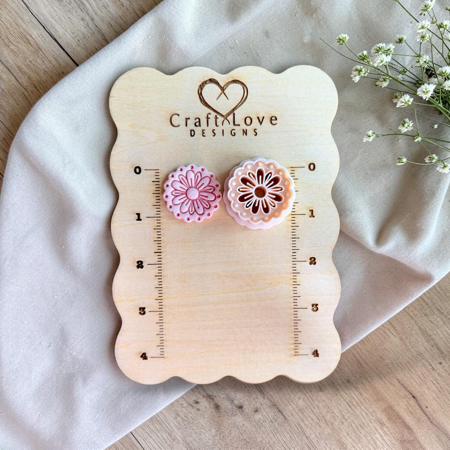 Daisy polymer clay cutter with scalloped edge on wooden sizing board