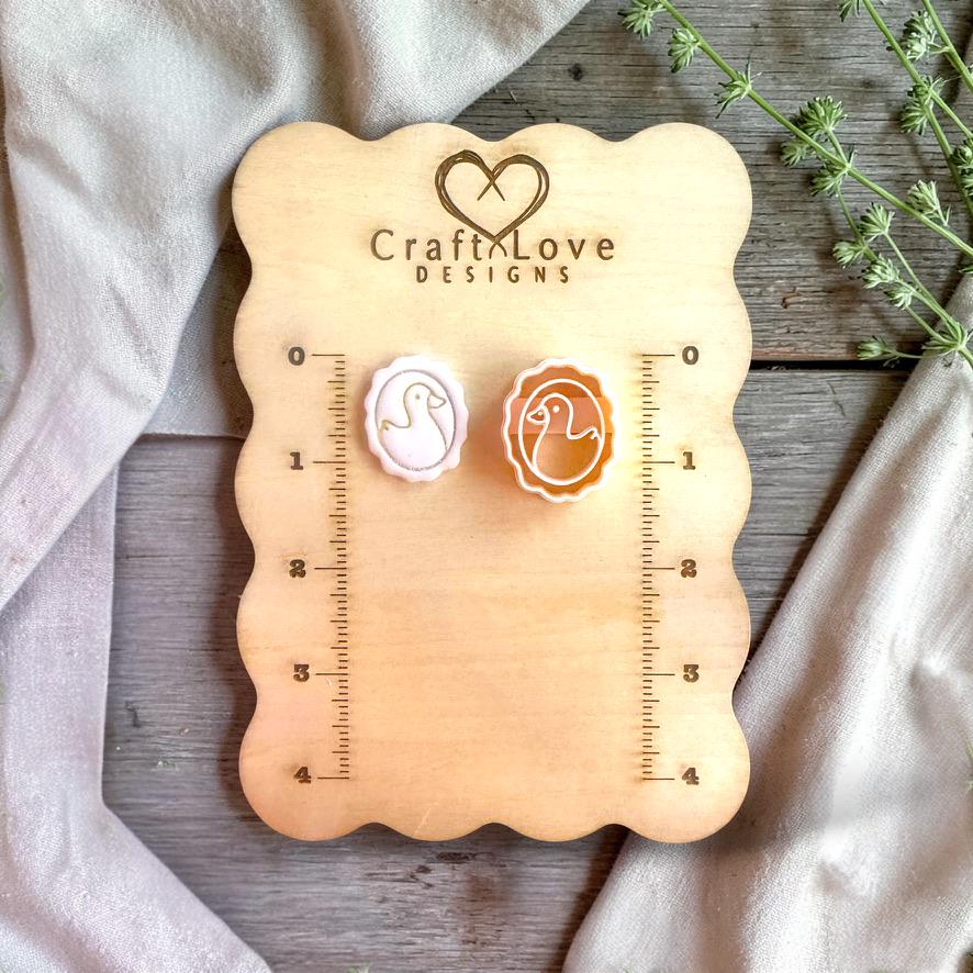 Duck cameo cutter and finished clay piece displayed on wooden measurement board