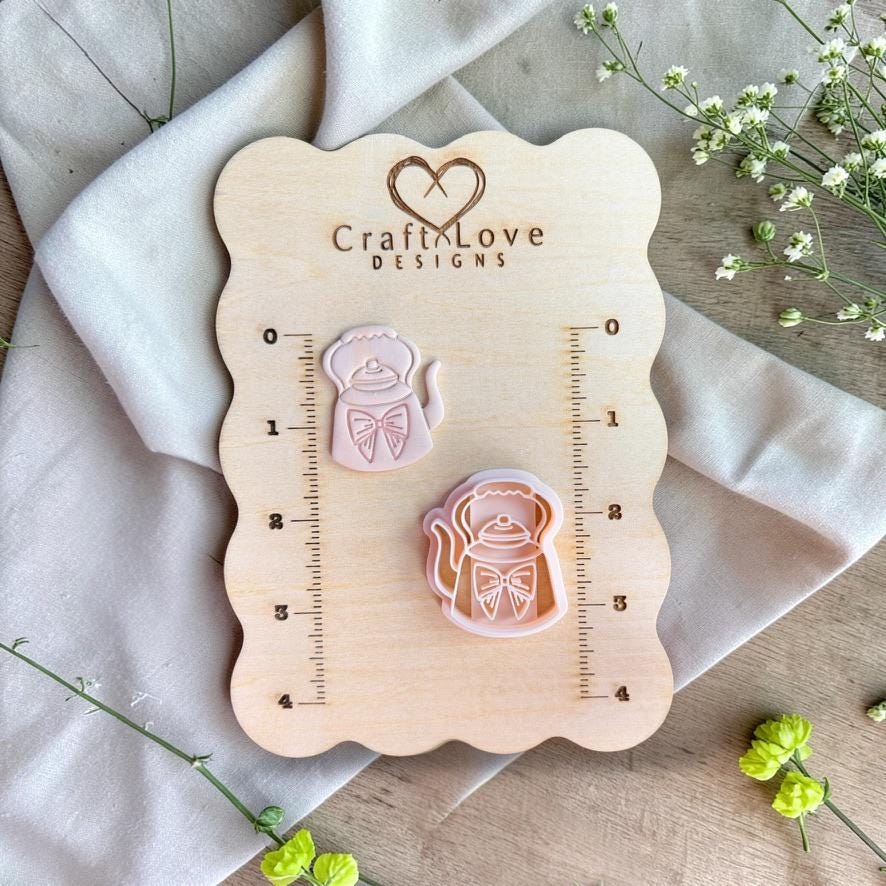 Teapot cutter and clay piece displayed on wooden measurement board