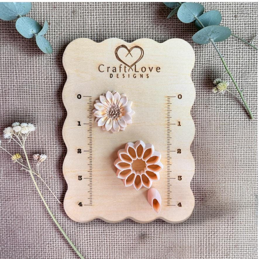 Sunflower clay sample with petal detail next to cutter and petal tool on wooden measurement board