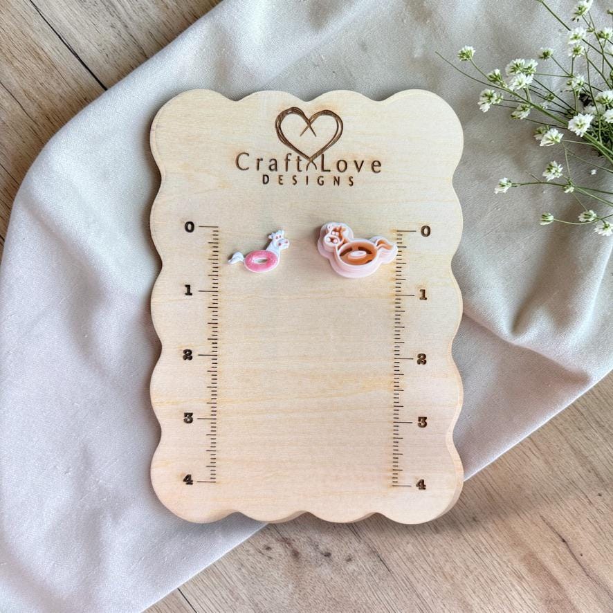 Cow floatie cutter and finished clay piece displayed on wooden ruler board