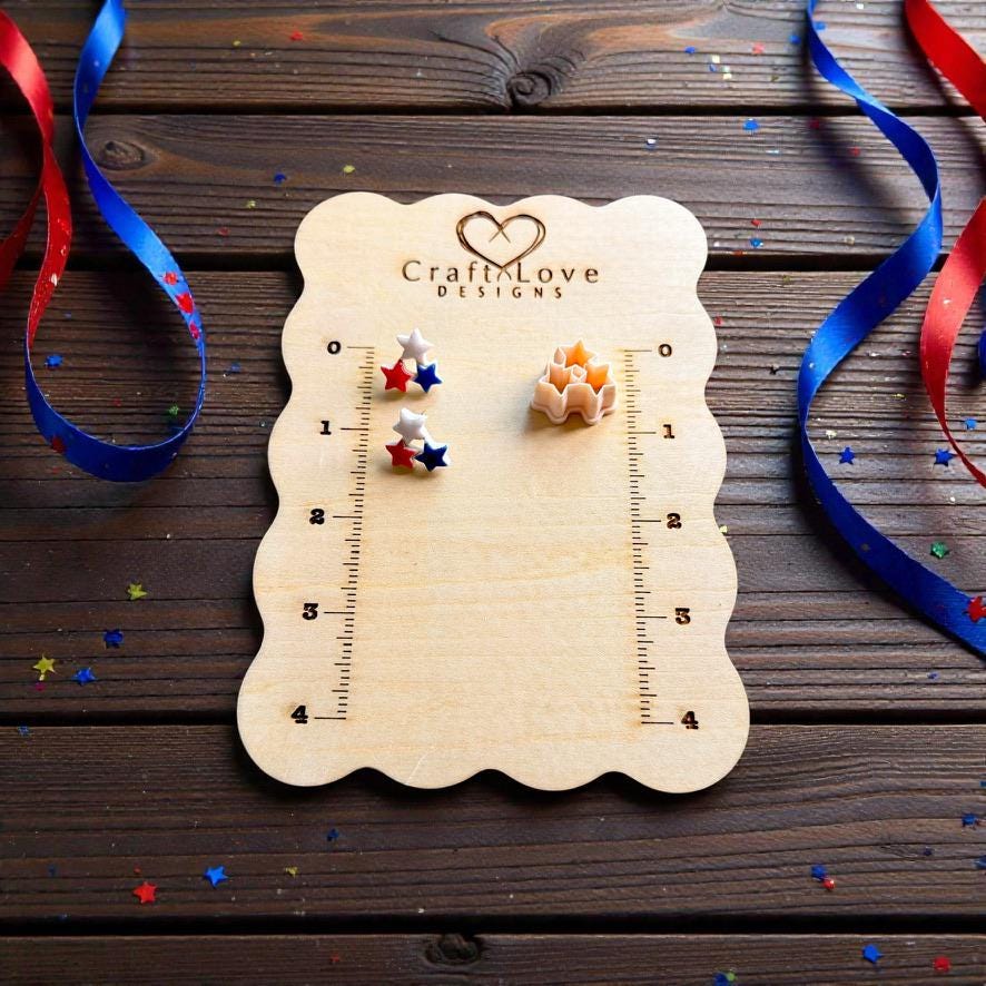 Patriotic triple star stud earrings and clay cutter displayed on wooden measurement board with festive ribbon and confetti
