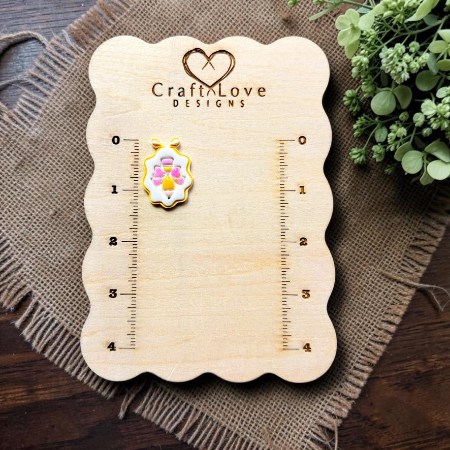 Finished pencil with bow framed polymer clay earring displayed on the Craft Love Designs measurement board.