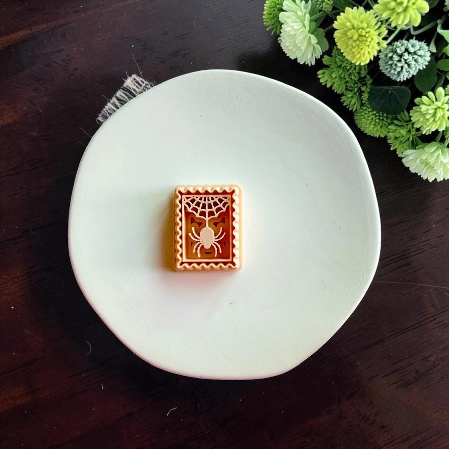 Spider web polymer clay cutter displayed alone on a white dish.