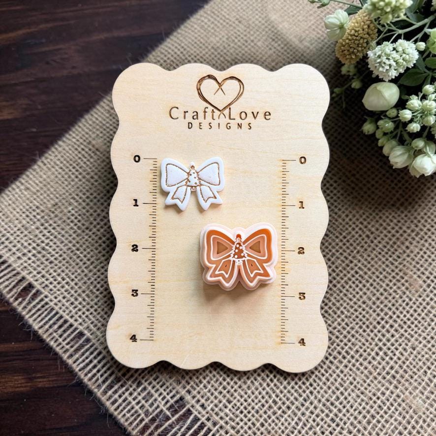 Christmas bow cutter and finished clay example displayed on a Craft Love Designs measurement board to show scale.