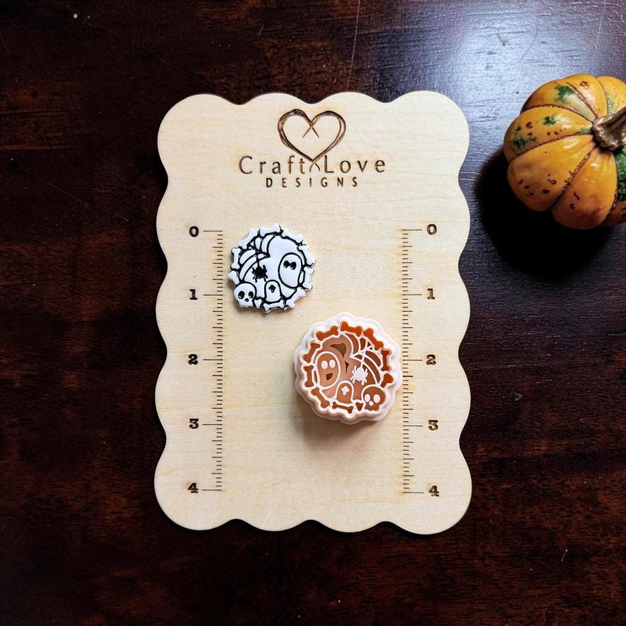 Spooky polymer clay cutter and black-and-white example clay piece displayed on a wooden measurement board with Halloween pumpkin decor.
