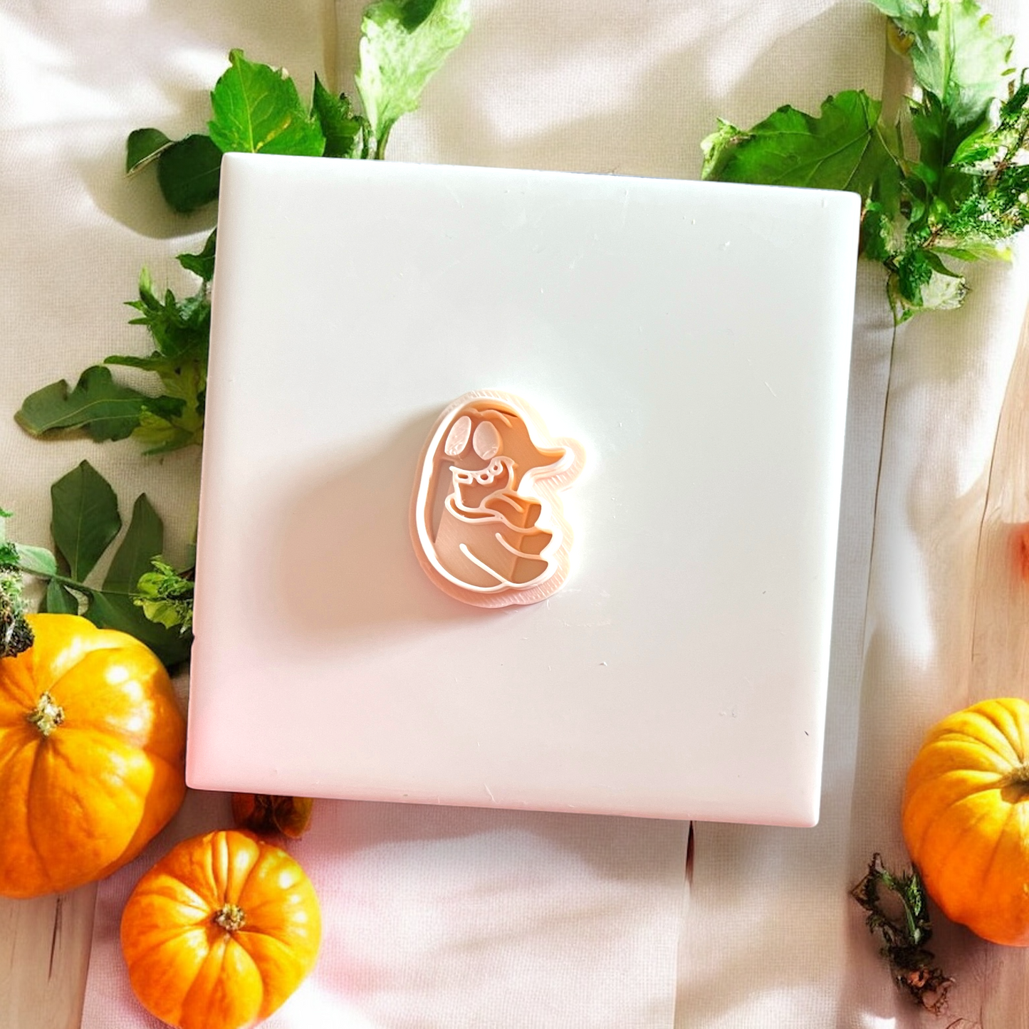 Silly Ghost polymer clay cutter centered on white tile with pumpkin accents