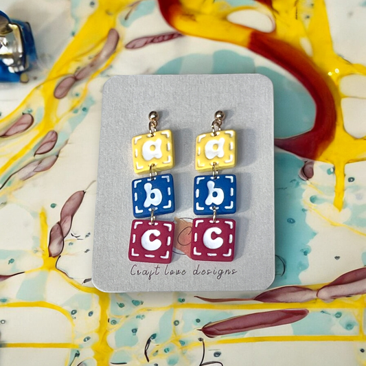 Colorful ABC block earrings displayed on a Craft Love Designs card, perfect for teachers or playful accessory lovers..