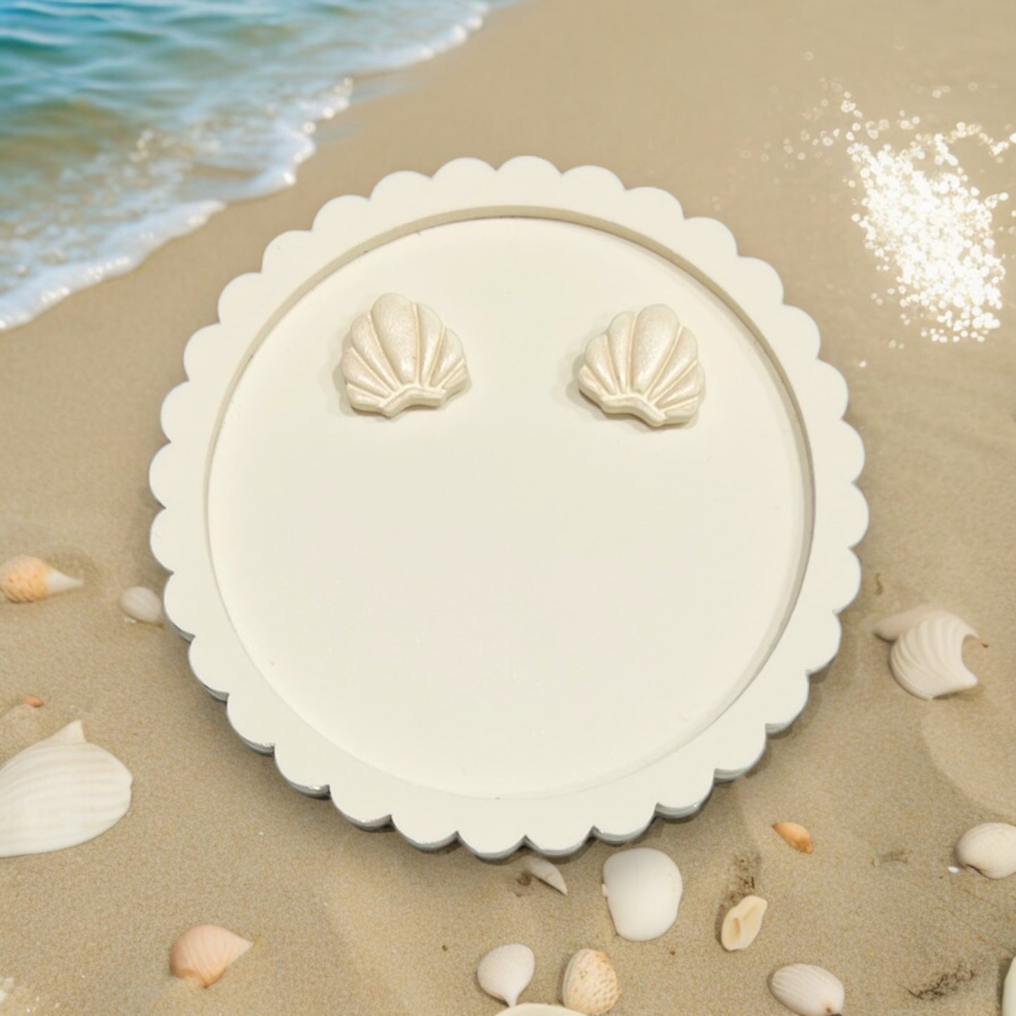  Ivory seashell stud earrings displayed on a white plate with coastal details, evoking serene beachside elegance. 
