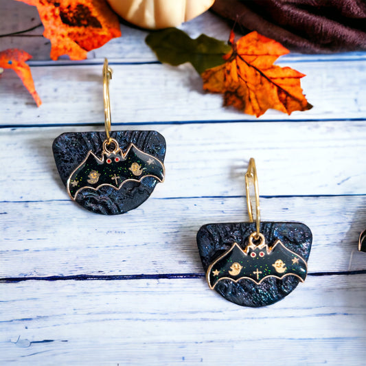 Black bat dangle earrings featuring glittery textured bases and gold bat charms with spooky ghost details, perfect for Halloween